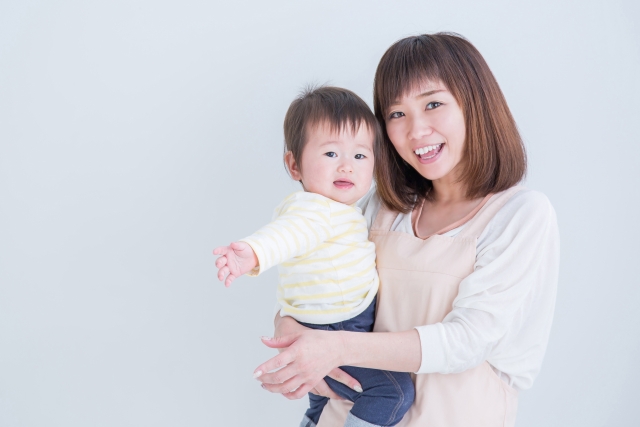 赤ちゃんを抱いて微笑む産後のママ